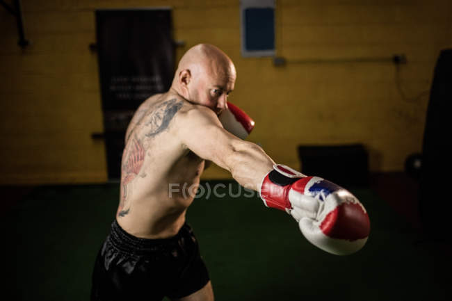 Shirtless tattooed thai boxer practicing in gym — Stock Photo