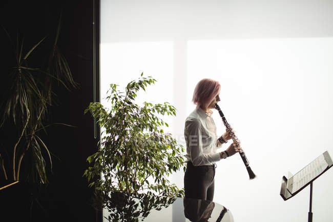 Внимательная женщина играет на кларнете в музыкальной школе — стоковое фото