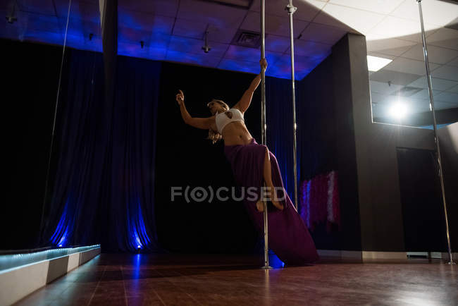 Bailarina de poste practicando pole dance en estudio - foto de stock