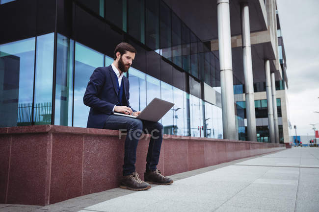 Homme d'affaires utilisant un téléphone portable à l'extérieur du bureau — Photo de stock