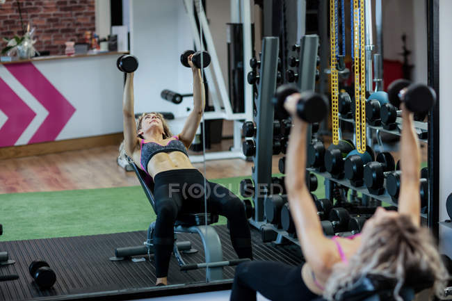 Hermosa mujer levantando pesas en el gimnasio - foto de stock