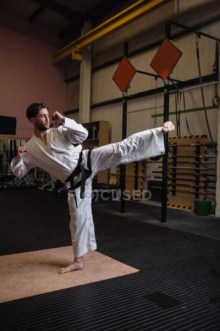 Vista lateral del hombre practicando karate en gimnasio - foto de stock