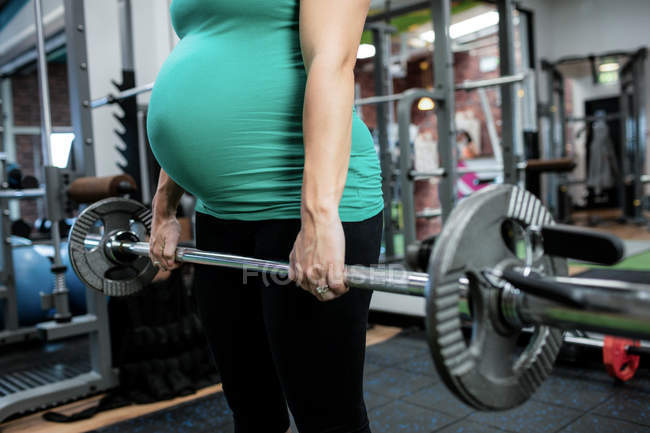 Mulher grávida trabalhando com barbell no ginásio — Fotografia de Stock