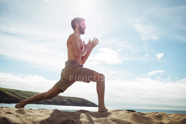 Homem realizando exercício de alongamento na praia — Fotografia de Stock