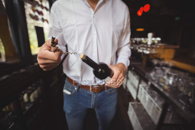 Sezione centrale del bar tender che apre una bottiglia di vino al bancone del bar — Foto stock