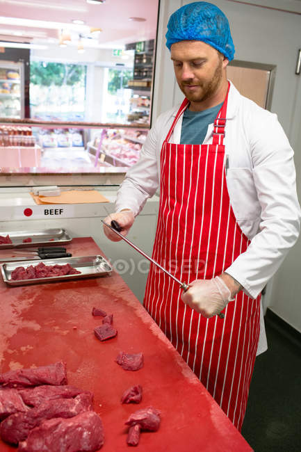 Butcher sharpening knife in butchers shop — Stock Photo