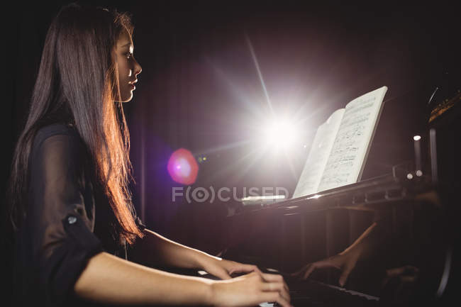 Beautiful woman playing a piano in music studio — Stock Photo