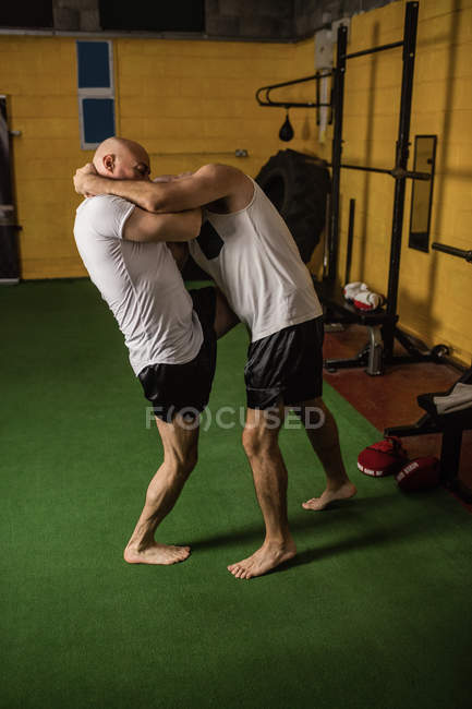 Vista laterale di due muay thai boxer che praticano in palestra — Foto stock