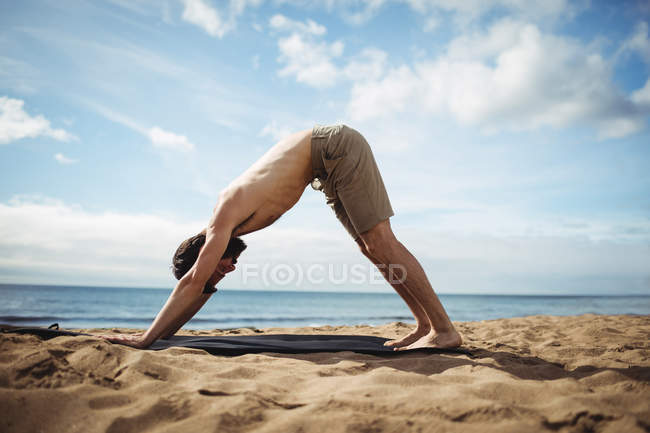 Человек, занимающийся йогой на пляже — стоковое фото