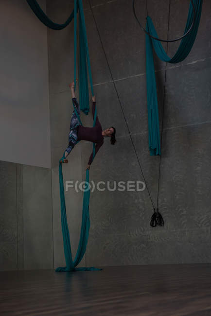 Gimnasta ejercitándose sobre cuerda de tela azul en gimnasio - foto de stock