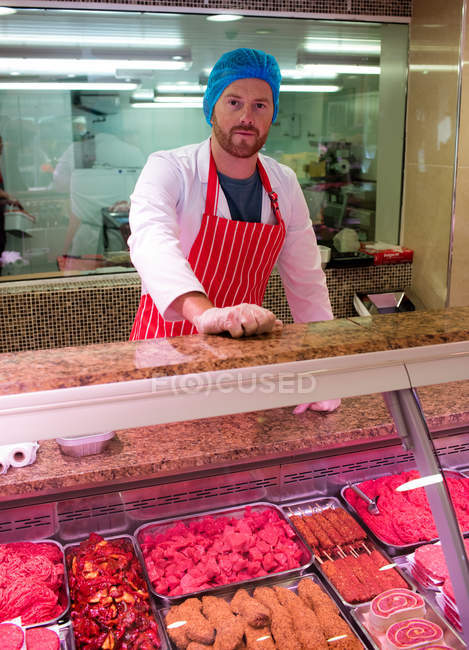Retrato de açougueiro em pé no balcão de carne no açougue — Fotografia de Stock