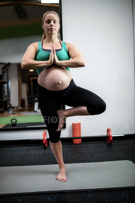 Mujer embarazada realizando yoga en el gimnasio - foto de stock