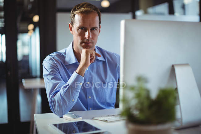 Portrait of businessman using desktop pc in office — Stock Photo