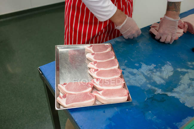 Sezione media del macellaio che organizza bistecche in vassoio in macelleria — Foto stock