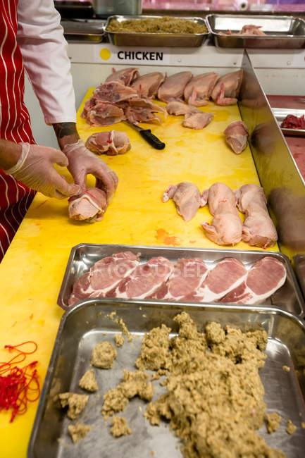 Mid section of butcher preparing a chicken and steak roll in butchers shop — Stock Photo