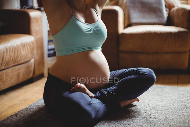 Immagine ritagliata di donna incinta che esercita in soggiorno a casa — Foto stock