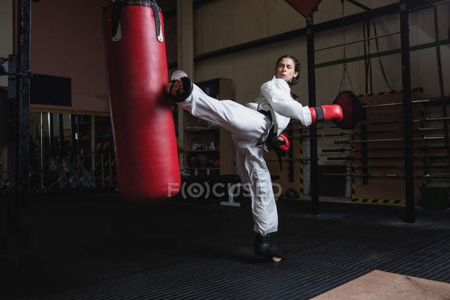 Forte Mulher praticando karatê com saco de perfuração no estúdio de fitness — Fotografia de Stock
