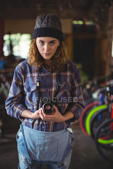 Portrait de femme ajustant la caméra vintage dans un magasin de vélos — Photo de stock