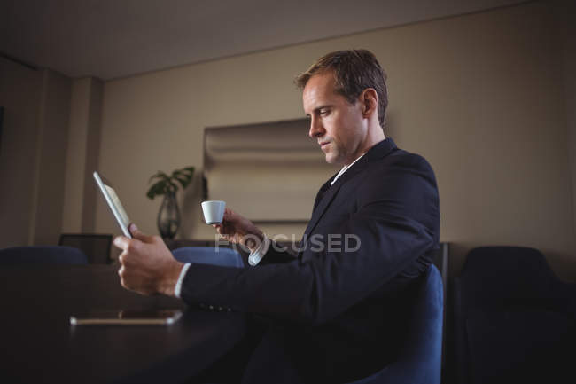 Бизнесмен использует цифровые планшеты во время кофе в офисе — стоковое фото