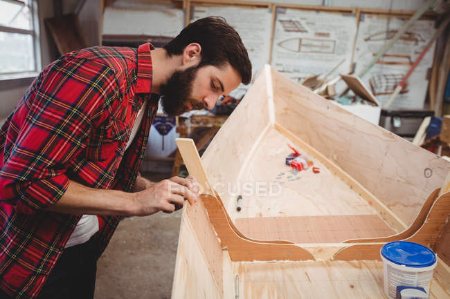 Man preparing wooden boat frame in boatyard — Stock Photo
