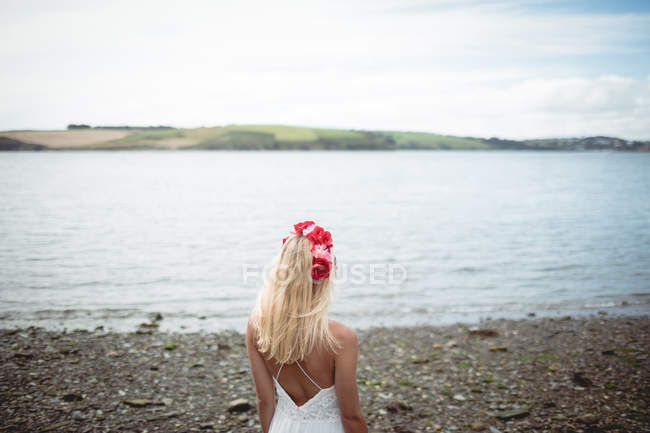 Visão traseira da mulher loira despreocupada em tiara flor de pé perto do rio — Fotografia de Stock