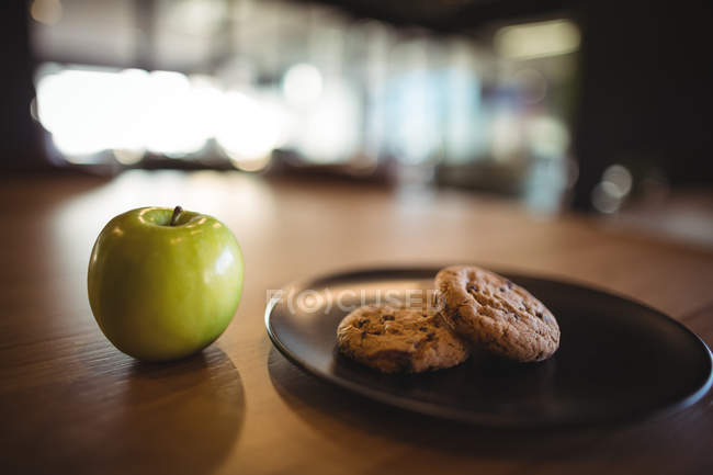 Зеленое яблоко и печенье на столе в кафе — стоковое фото