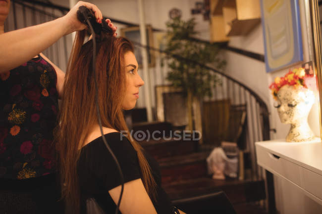 Mulher recebendo cabelo endireitado no salão de cabeleireiro — Fotografia de Stock