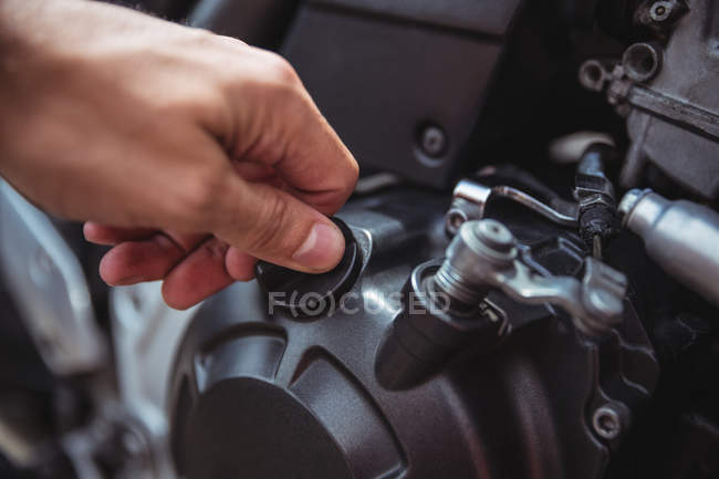 Hand of mechanic closing oil tank of motor bike at workshop — Stock Photo