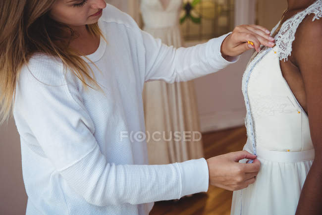 Woman trying on wedding dress in a studio with the assistance of fashion designer — Stock Photo