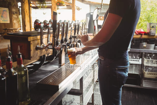 Seção intermediária do concurso de bar enchendo cerveja da bomba de bar no balcão de bar — Fotografia de Stock