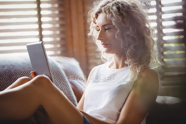Bella donna che utilizza tablet digitale in soggiorno a casa — Foto stock