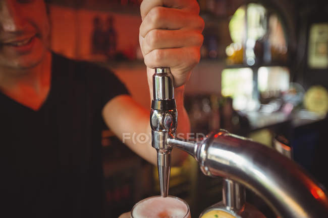 Primo piano del bar tender che riempie la birra dalla pompa bar al bancone del bar — Foto stock