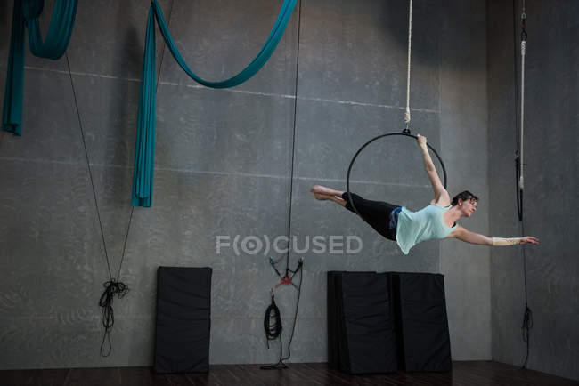 Mujer joven realizando gimnasia en el aro en el gimnasio - foto de stock