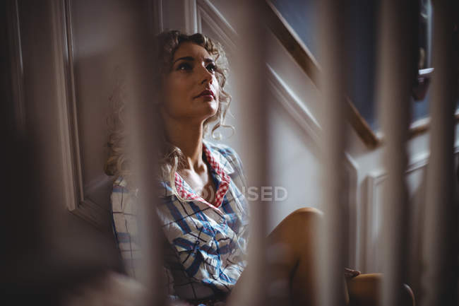 Mulher pensativa sentada na escada em casa — Fotografia de Stock