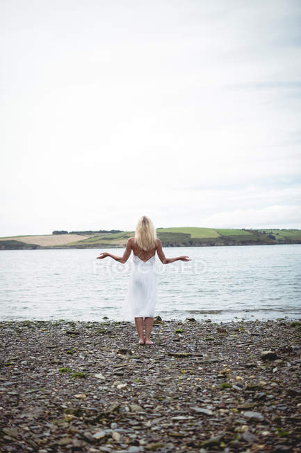 Вид ззаду безтурботну блондинку, що стоїть біля річки — стокове фото