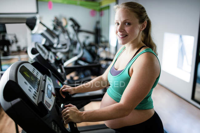 Portrait of pregnant woman exercising on treadmill at gym — Stock Photo