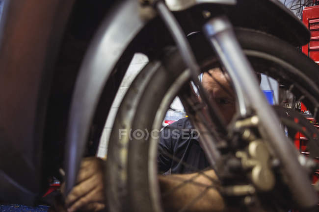Primo piano del meccanico che esamina la moto in officina — Foto stock