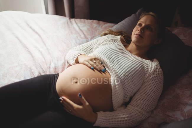 Vista ad alto angolo di premurosa donna incinta rilassante in camera da letto a casa — Foto stock