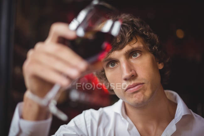 Barista guardando un bicchiere di vino rosso al bancone del bar — Foto stock