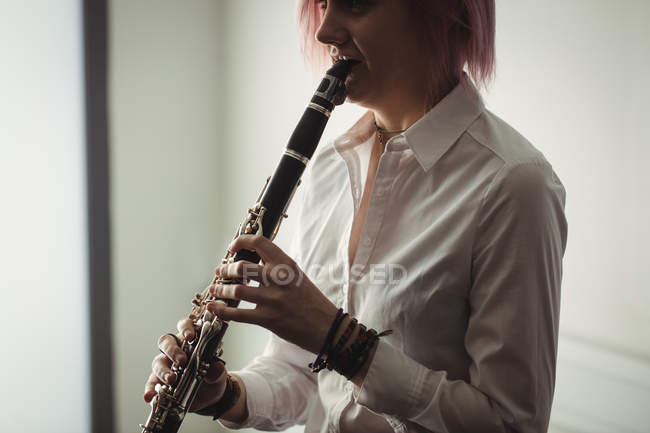 Mulher bonita tocando um clarinete na escola de música — Fotografia de Stock