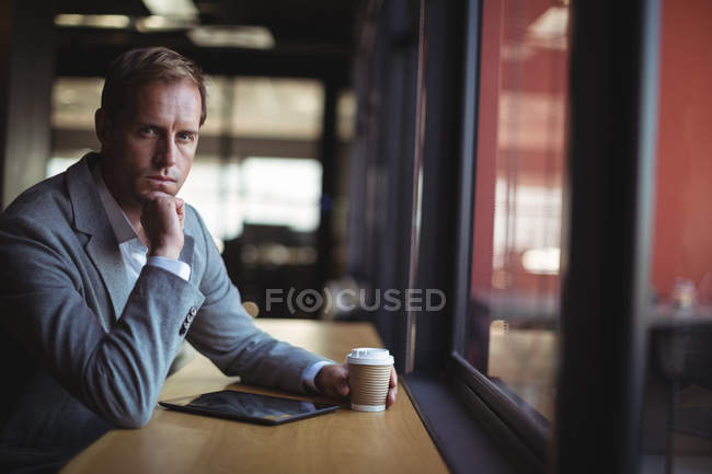Retrato de homem de negócios sentado no café com um tablet digital e café — Fotografia de Stock