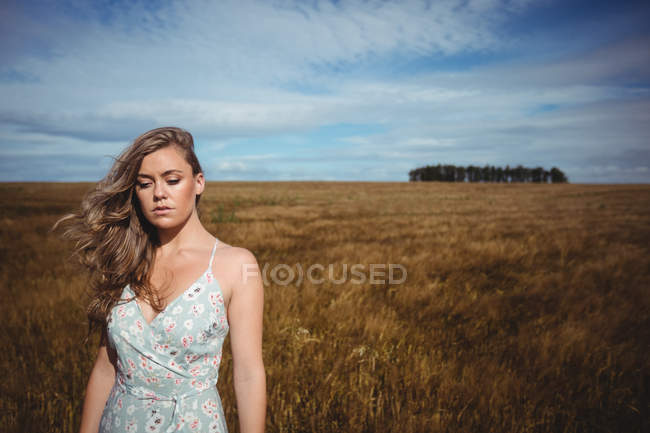 Жінка, стоячи в пшеничному полі на сонячний день в сільській місцевості — стокове фото