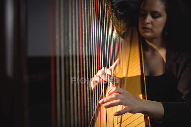 Donna attenta suonare un'arpa nella scuola di musica — Foto stock