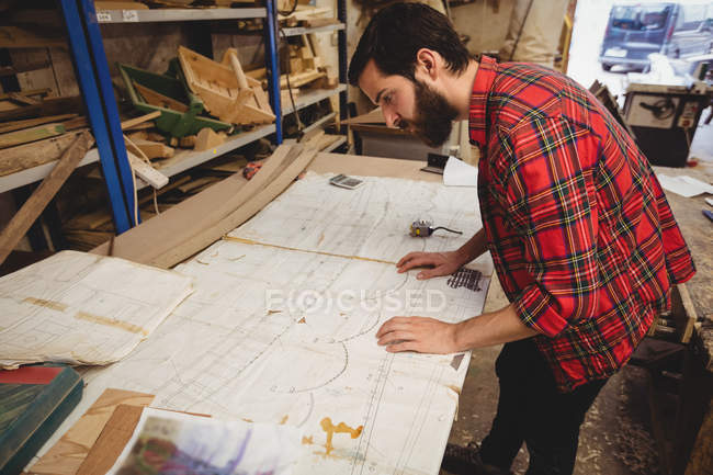 Man looking at blueprint in boatyard interior — Stock Photo