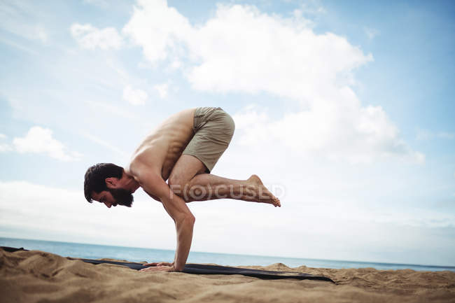 Человек, занимающийся йогой на пляже — стоковое фото