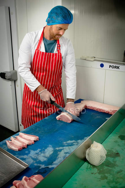 Boucher tranchant de la viande au comptoir de boucherie — Photo de stock
