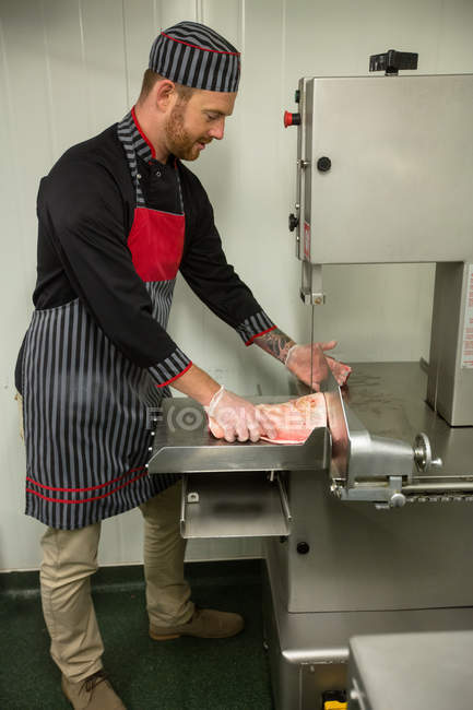 Macellaio che taglia carne di maiale in macchina in macelleria — Foto stock