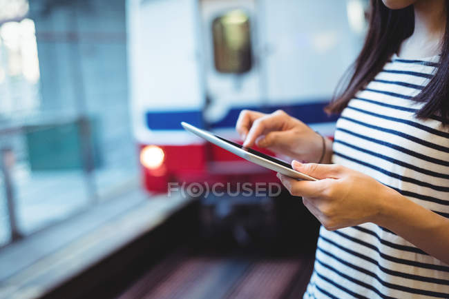 Розділ середині жінка, використовуючи цифровий планшет на залізничному вокзалі — стокове фото