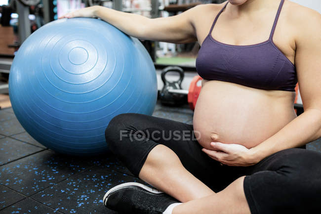 Schwangere hält ihren Bauch in Turnhalle — Stockfoto