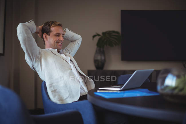 Счастливый бизнесмен сидит в офисе — стоковое фото